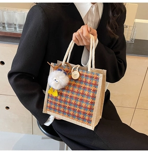 Close-up of linen tote bag with vibrant plaid pattern and fuzzy bird keychain detail