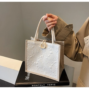 Detailed macro view of 3D rose relief fabric and woven rope handle on linen tote