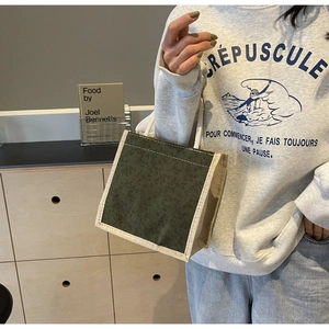 Dettaglio della borsa in tessuto verde scuro con bordo e manico in tela beige