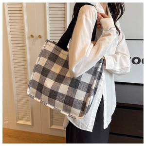 Détail du cabas en toile à damier montrant le tissage texturé et la bandoulière noire robuste