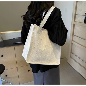 Gros plan du sac fourre-tout beige avec texture jacquard rose et anses en toile