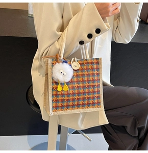 Detail of retro plaid linen handbag featuring a large button and plush white charm