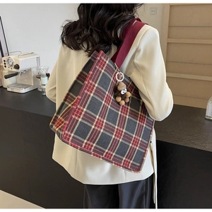 Vista dettagliata di una grande borsa tote in tela a quadri con un ciondolo in peluche