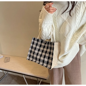 Detail of checkered woven tote bag with white rope handles on a minimalist background