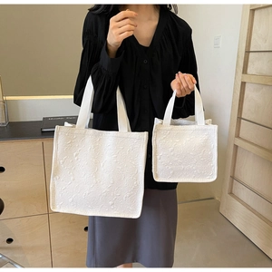 Détail du tissu jacquard floral blanc gaufré sur de grands sacs fourre-tout