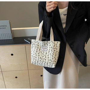 Gros plan du sac cabas en velours côtelé fleuri avec anses tissées et étiquette logo
