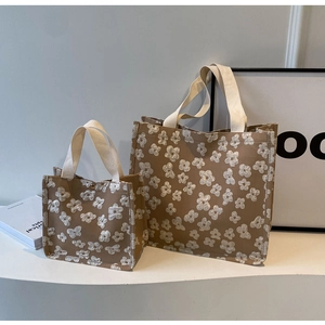 Detailed view of daisy jacquard fabric and durable webbing handles on canvas tote bags