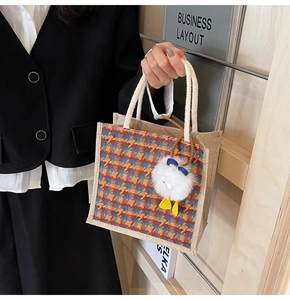 Close-up of linen tote bag with colorful houndstooth pattern and plush duck pendant