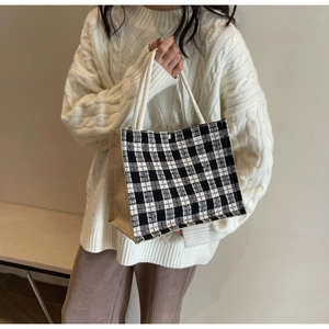 Detail of checkered woven tote with brown canvas side panels and rope handles