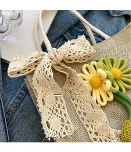 Vue détaillée du sac tissé beige avec nœud en dentelle et broderie florale raffinée