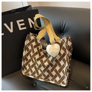 Detail of knitted tote bag with beige canvas handles and white heart plush keychain charm
