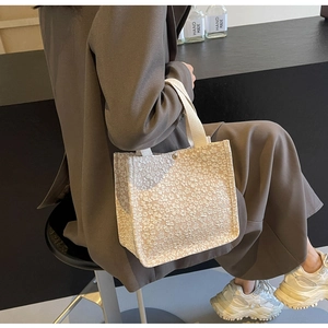 Détail de la texture dentelle à relief floral sur un grand sac cabas en toile beige