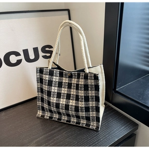 Macro shot of the black and white checkered woven fabric and rope handle of the tote bag
