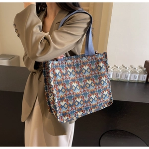 Detail of bohemian woven tote bag with colorful geometric patterns and blue shoulder strap