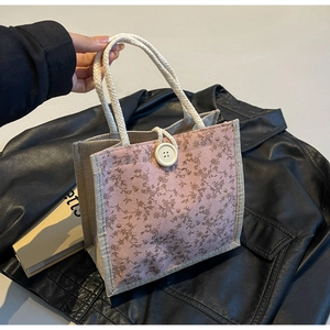 Dettaglio della borsa a fiori con motivo rosa, bottone e manici in corda