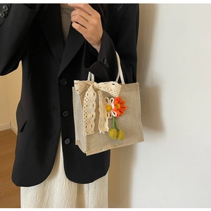 Détail du sac en lin avec nœud en dentelle et décorations de tournesol au crochet