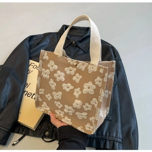 Close-up of khaki canvas tote featuring white 3D floral textures and metal buckle
