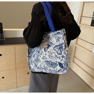 Close-up of canvas tote bag with vintage blue butterfly pattern and sky blue straps