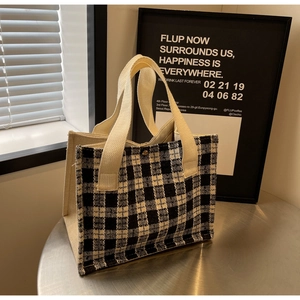 Close-up of black and white plaid woven tote bag with vintage gold metal buckle