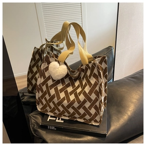Detail of woven tote bag featuring geometric brown patterns and a plush heart charm