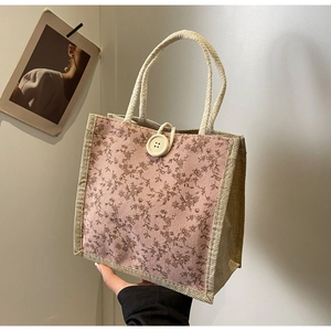 Dettaglio borsa in lino floreale con bottone beige e manico in corda intrecciata