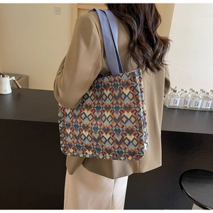 Detail of bohemian woven tote bag with colorful geometric patterns and blue straps