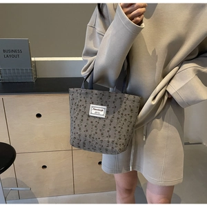 Gros plan du sac cabas en velours côtelé fleuri avec texture vintage et écusson