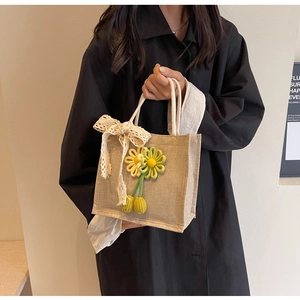 Détail d'un sac en jute orné d'une fleur de tournesol au crochet et d'un nœud en dentelle