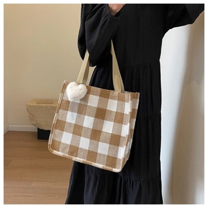 Détail du sac fourre-tout à damier jaune-brun avec texture tissée et breloque cœur