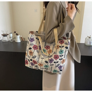 Detail of floral canvas tote bag with woven handles and vintage botanical print pattern