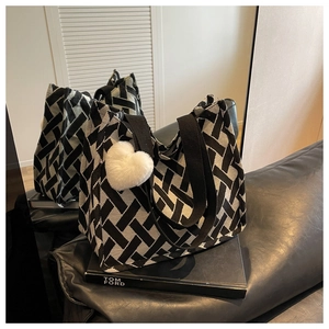 Macro view of woven black and white tote bag with plush heart charm on a sofa