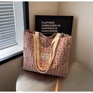 Gros plan d'un sac cabas en velours rose avec motifs floraux sombres et anses blanches
