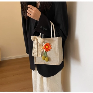 Détail du sac cabas en jute avec nœud en dentelle et fleurs tissées colorées
