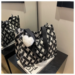 Detail of black and white woven canvas tote bag with heart charm and ribbon handles