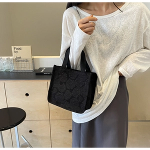 Gros plan sur un sac cabas noir avec texture jacquard rose et design de forme carrée