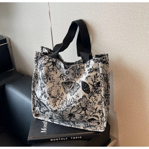 Detail view of large canvas tote bag with black and white floral and butterfly prints