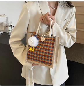 Close-up of retro plaid tweed handbag with white rope handle and fuzzy monster charm