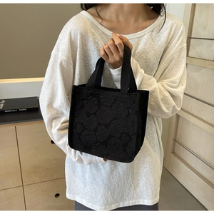 Détail du sac cabas noir avec tissu jacquard à motifs roses et larges poignées