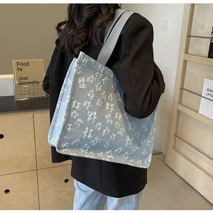 Close-up of light blue tote bag featuring 3D floral texture and nylon handles