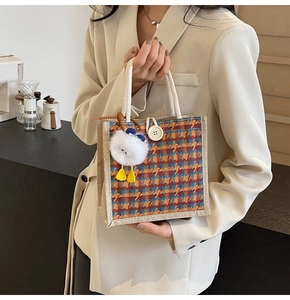 Detailed shot of a houndstooth bento bag with cotton rope handles and cute duck pendant