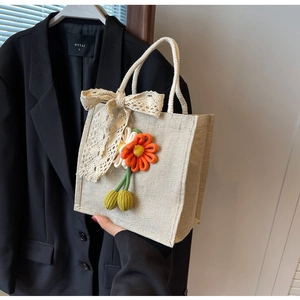 Détail d'un sac en lin tressé avec nœud en dentelle et fleurs en relief