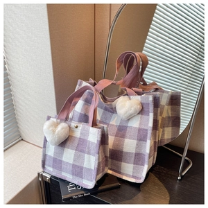 Detail of purple plaid woven tote bags featuring a soft white plush heart pendant