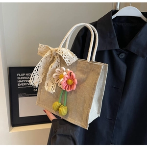 Détail du sac en jute avec fleurs tricotées et nœud en dentelle au style moderne