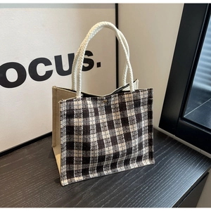 Close-up of woven rope handle on black and white checkered canvas tote bag