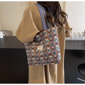 Detail of bohemian jacquard tote bag with geometric patterns worn over a camel coat