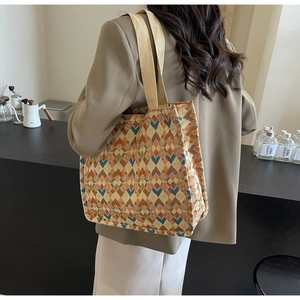 Detailed view of woven geometric tote bag with orange and teal diamond patterns