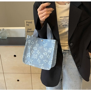 Detail of light blue tote bag with 3D floral texture and sturdy woven handles