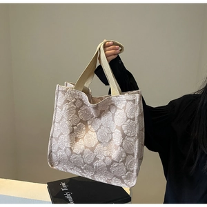 Détail d'un sac cabas jacquard beige clair avec motifs floraux et anse en sangle