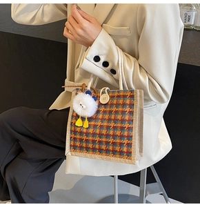 Close-up of houndstooth tote bag with cotton rope handles and white plush charm