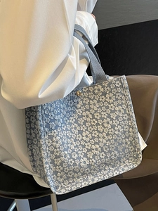 Sac cabas à fleurs bleu clair avec texture en dentelle et boucle dorée portée